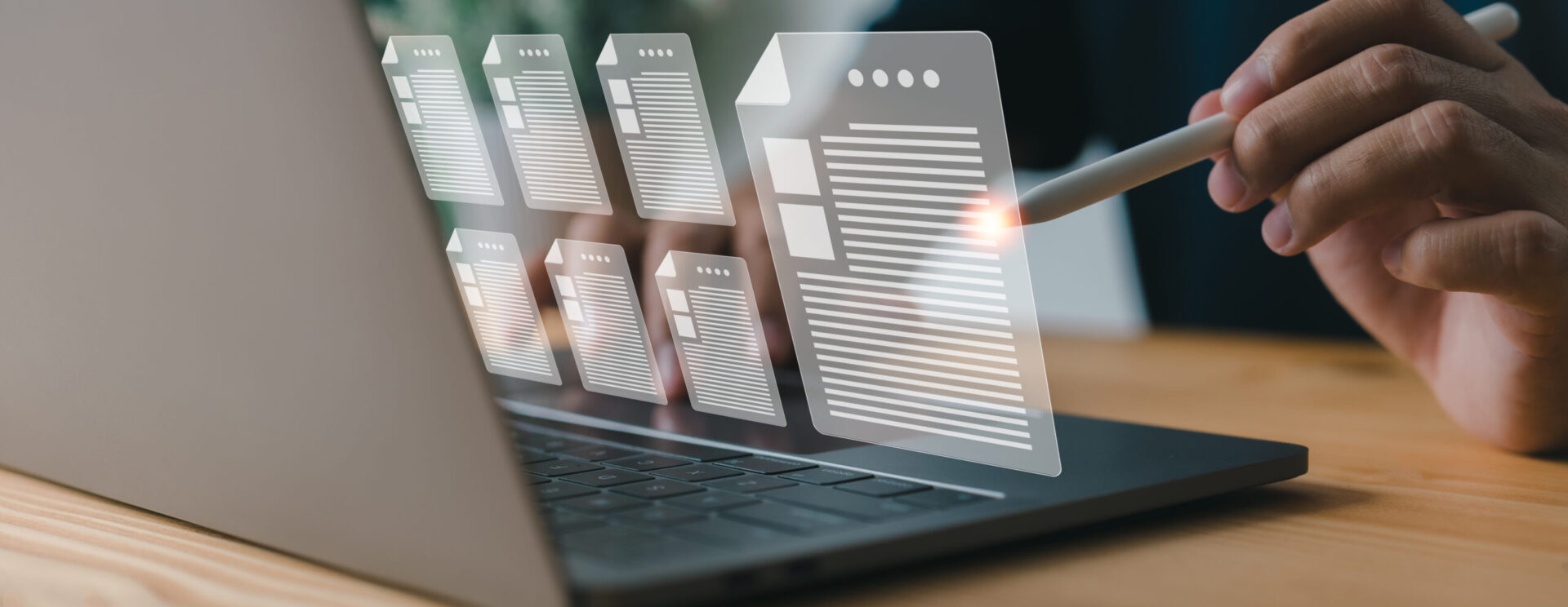 Une personne utilise un ordinateur portable et interagit avec des icônes de documents numériques affichées en transparence sur l’écran.